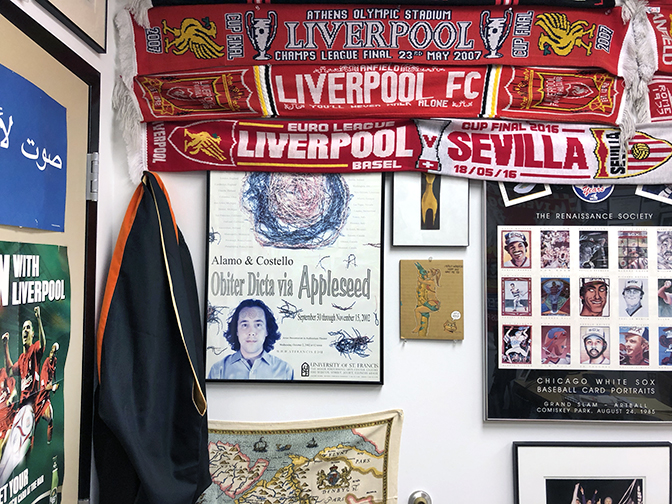 An exhibition poster is flanked by graduation attire, a Chicago White Sox poster produced by the Renaissance Society, Liverpool FC scarves/posters, and a map of Ireland.